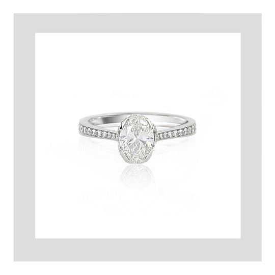 Platinum engagement ring featuring an oval diamond with a tappered ring band set with micro pavé set white diamonds.